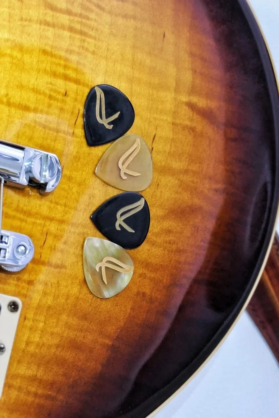 Close-up of guitar picks with the Wambooka logo on a wooden guitar body