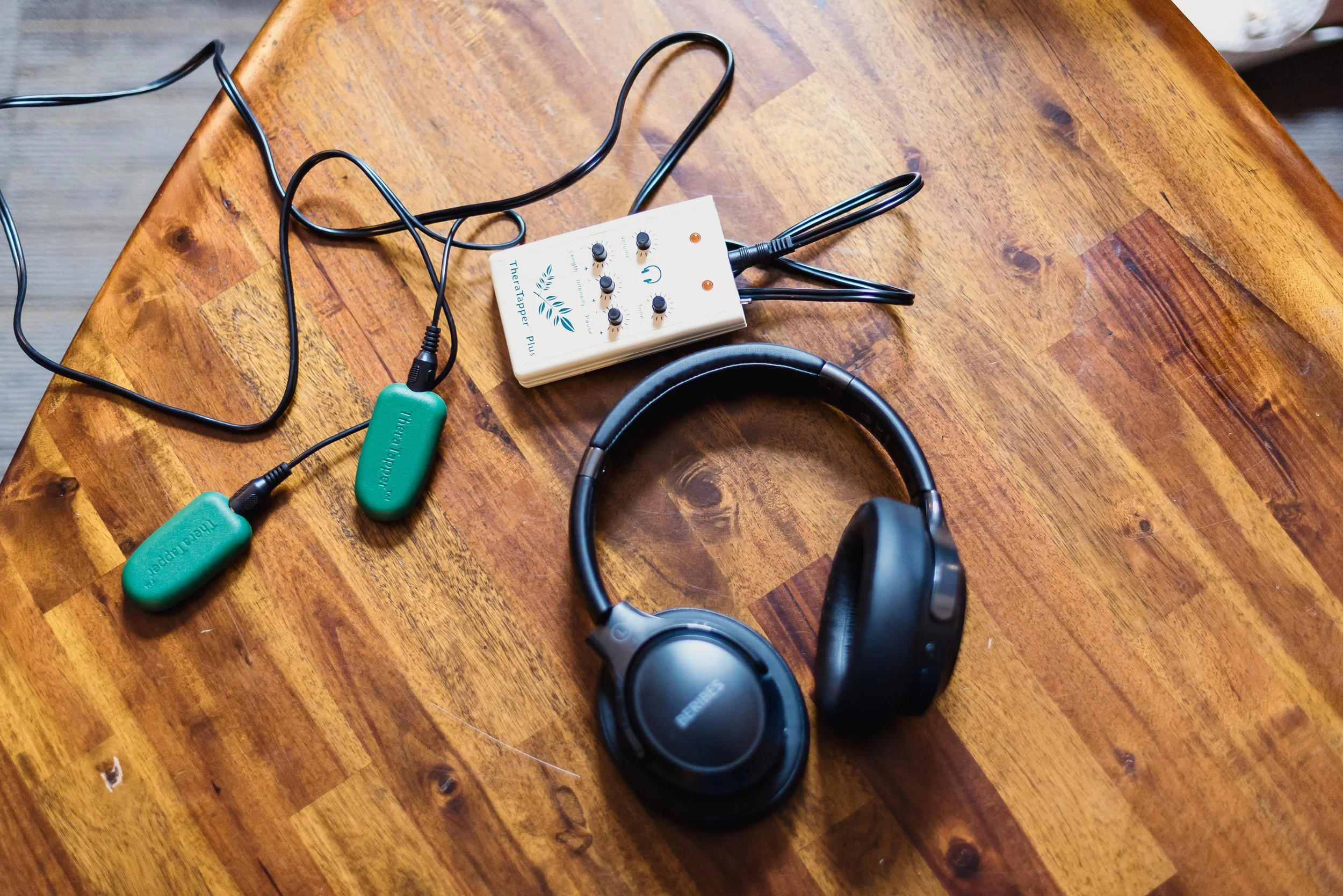 Vue aérienne d’une table en bois avec un casque, un dispositif audio avec des boutons et deux plaques vertes connectées par des câbles.