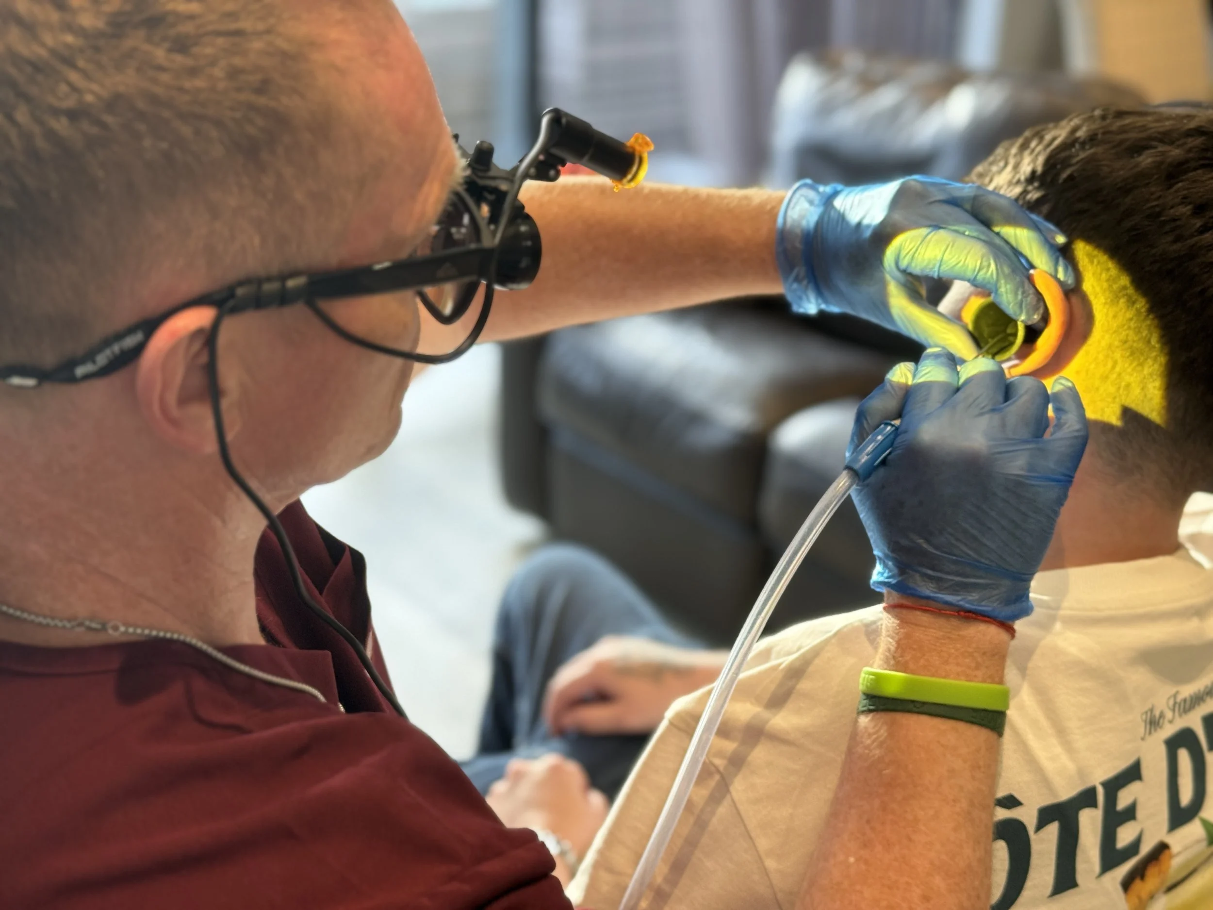 Ryan from Ear Care Dorset performing microsuction ear wax removal for a young man in a calm, neurodiverse-friendly home visit environment.