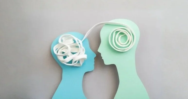 Paper art of two human profiles with brain shapes made of coiled paper, facing each other.