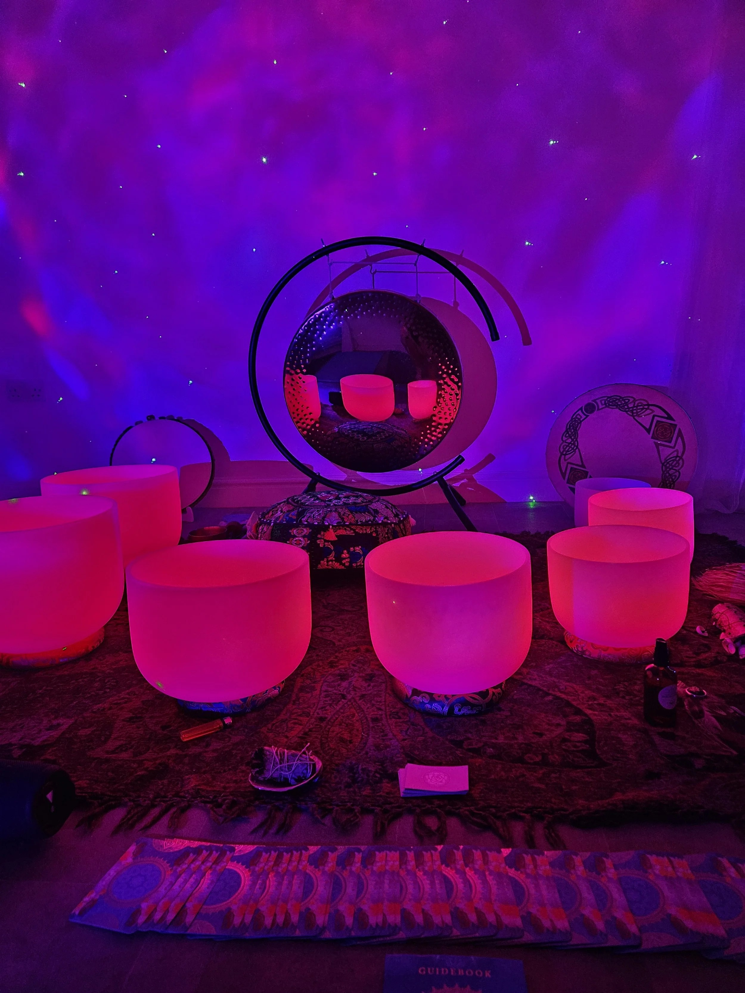 Room with glowing pink seating, hanging circular chairs, and a starry purple-lit ceiling creating a cosmic atmosphere.