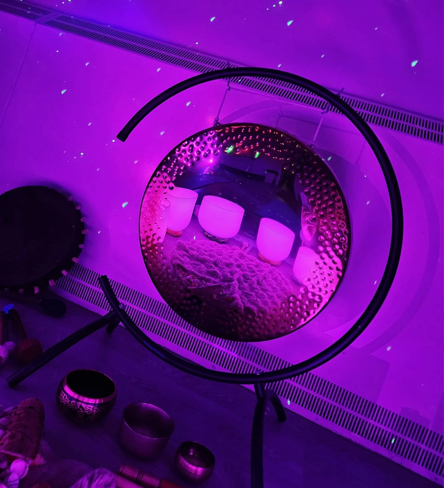 A circular mirror shows four purple glowing bowls on a fluffy surface inside a room with purple lighting and star-like light effects.