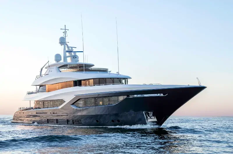 Large luxury yacht with multiple decks sailing on the ocean at sunset
