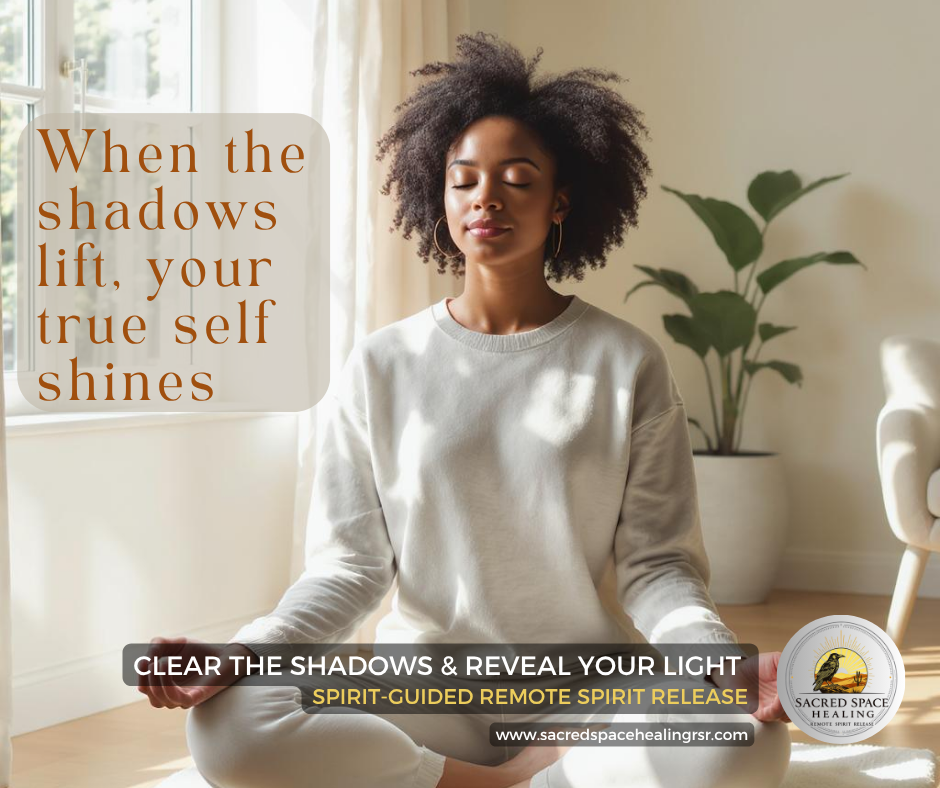 A woman with curly hair sits peacefully in a cross-legged position in a bright room near a window, practicing meditation or mindfulness with her eyes closed.
