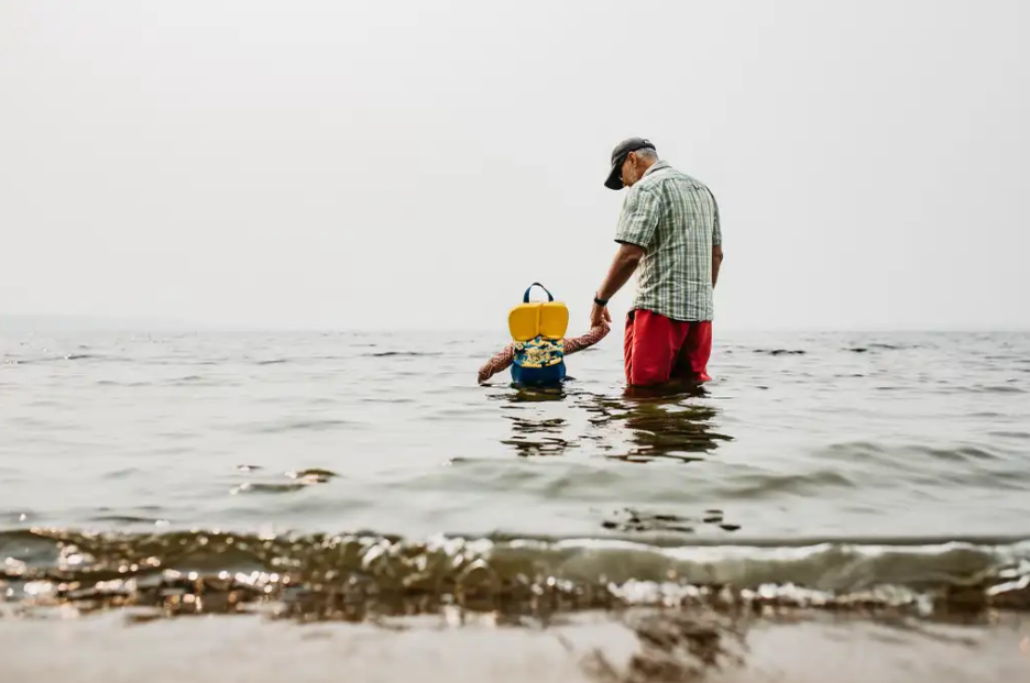 Author Denis Fortier and grandchild holding hands in a lake.