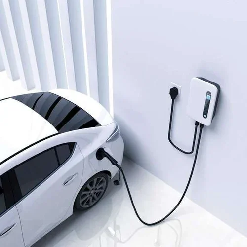 White electric car plugged into a wall charger indoors.
