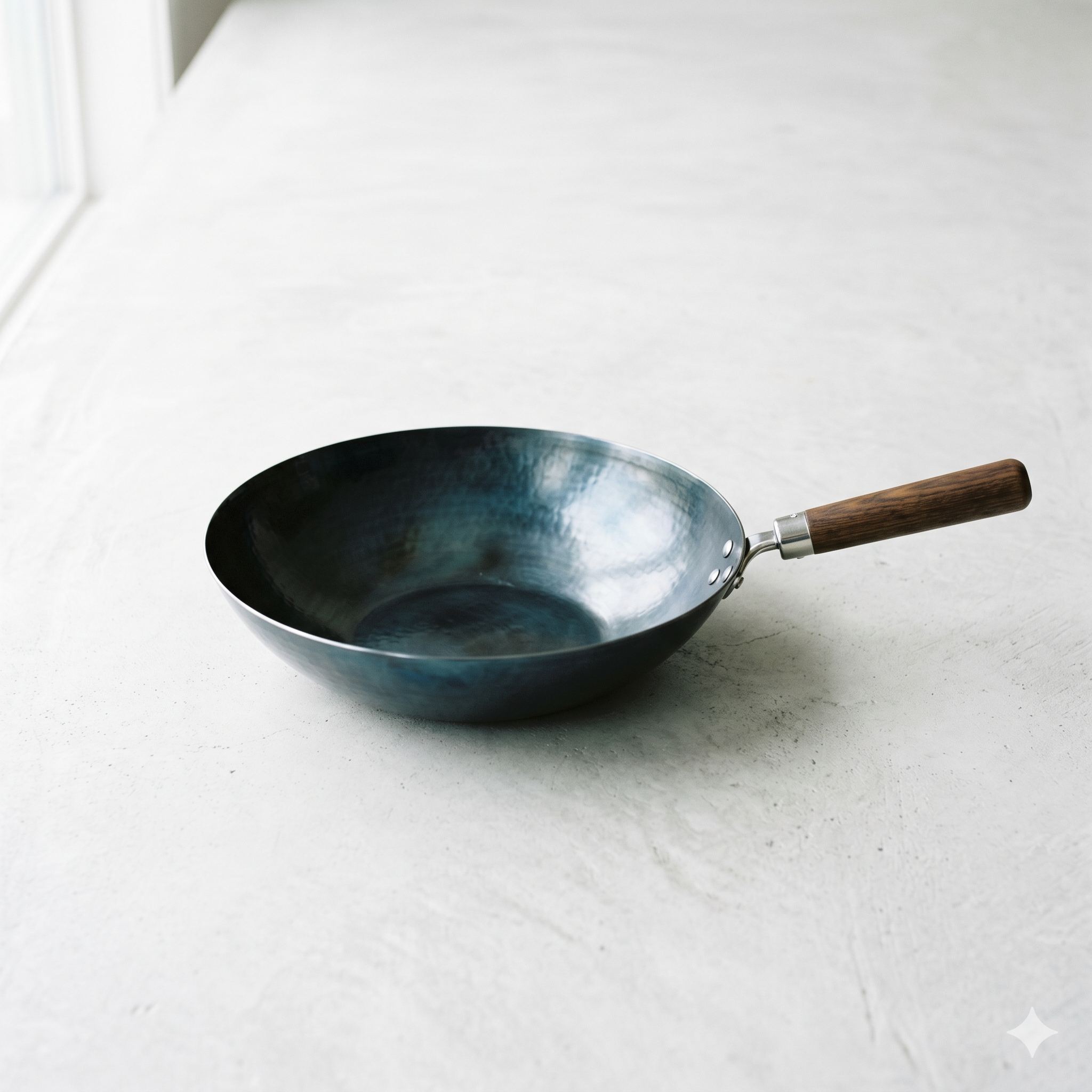 Professional catalog-style photograph of a 14-Inch Blue Carbon Steel Wok centered on a clean white matte concrete background, emphasizing high-end culinary infrastructure.