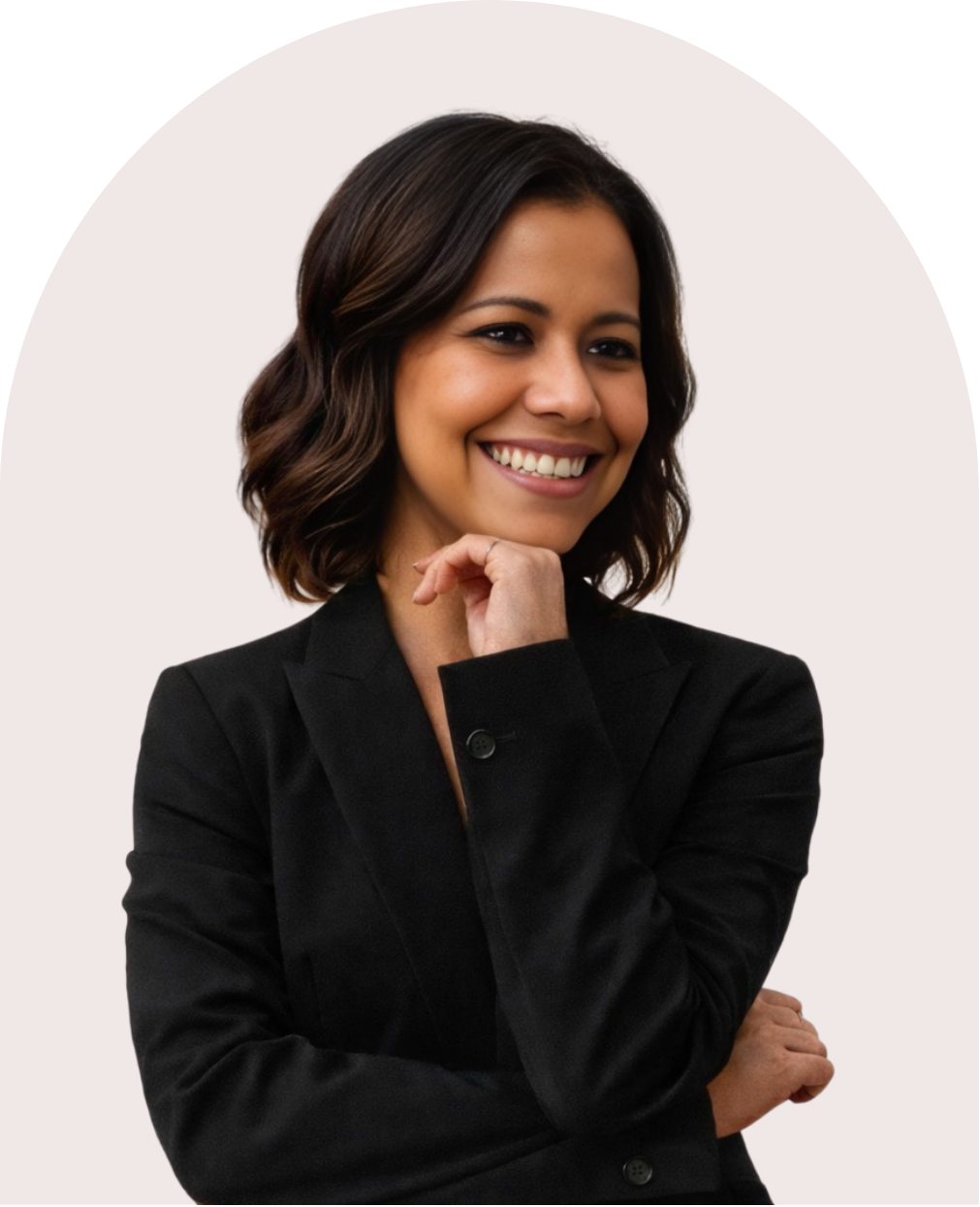 A woman with shoulder-length brown hair, wearing a black blazer, smiling with her hand resting on her chin, against a plain light background.