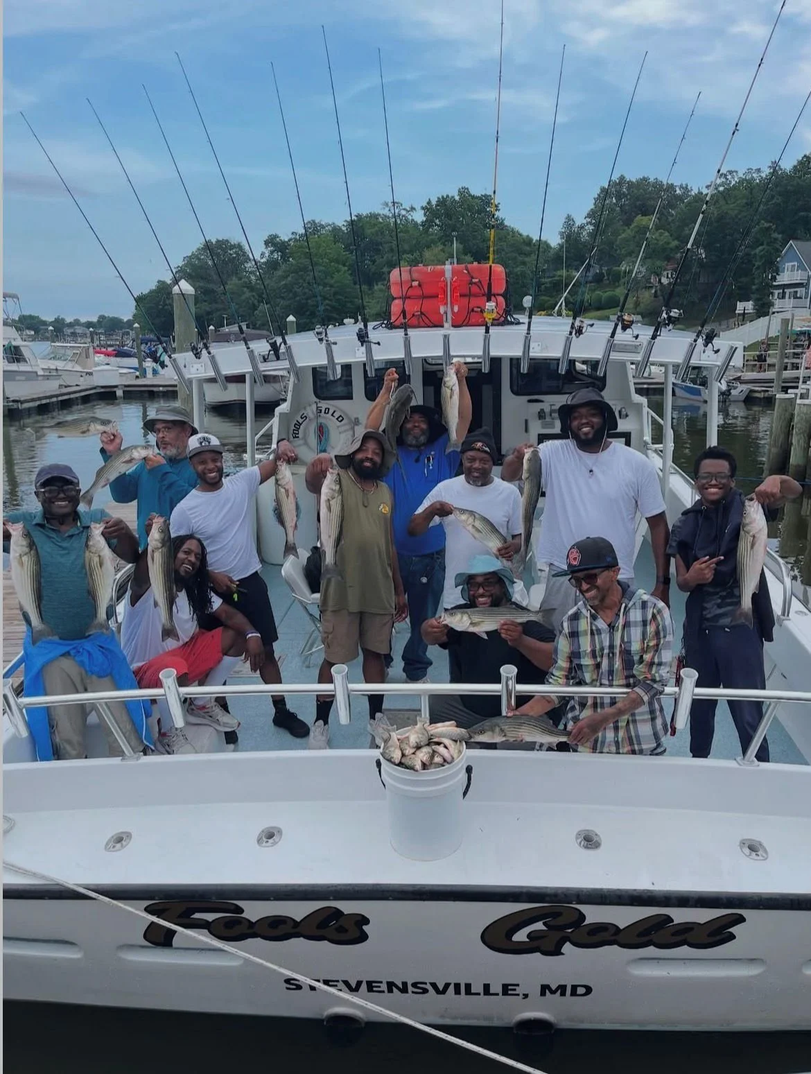 A group of people on a boat holding fish they caught during a fishing trip at a marina in Stevensville, Maryland.
