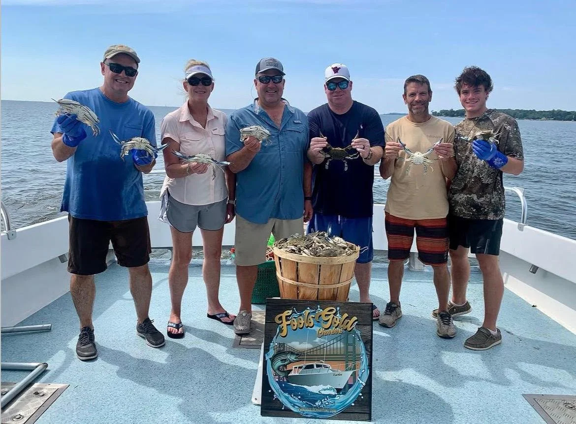 Group of seven people on a boat holding crabs, with a bucket of crabs in front and a sign that says 'Fabulous Crab Channel'.