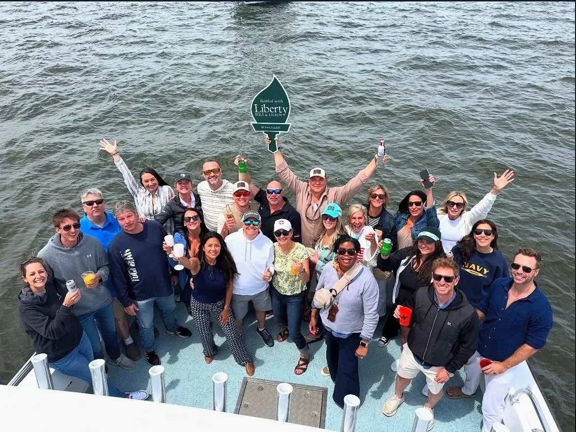 Group of people celebrating on a boat with water in the background, holding drinks and cheering.