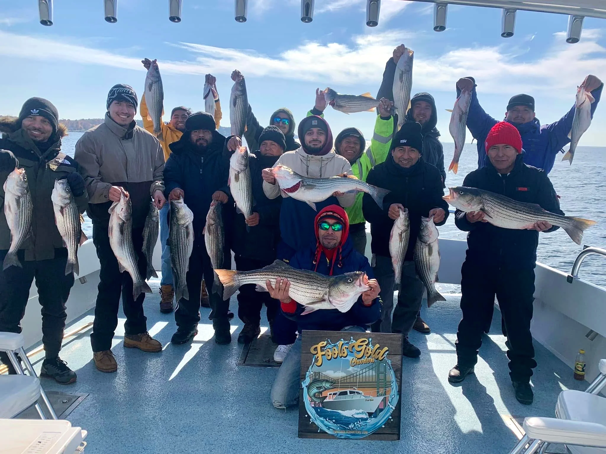 Group of anglers holding striped bass aboard Fools Gold.
