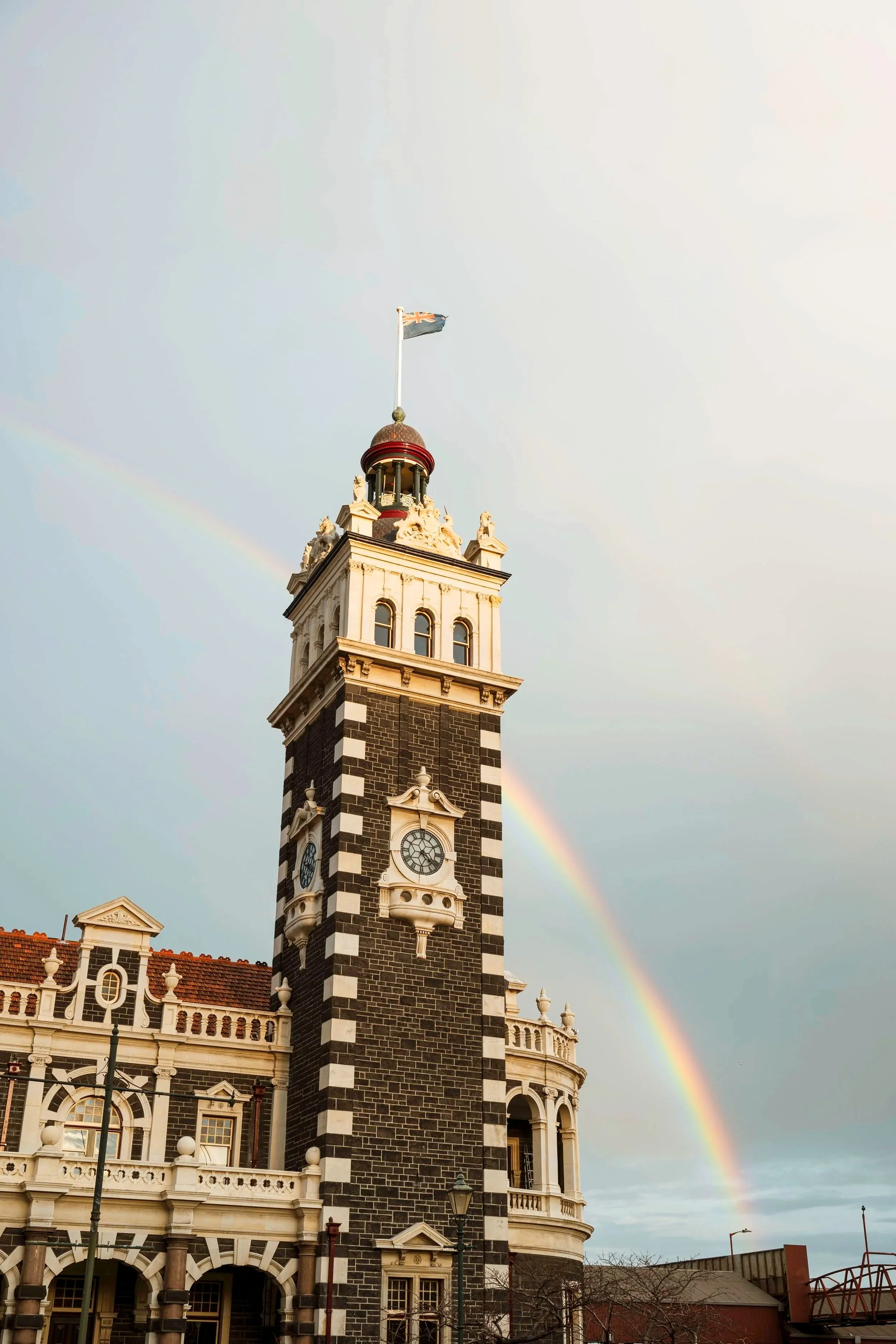 A historic clock tower with a rainbow in the background.