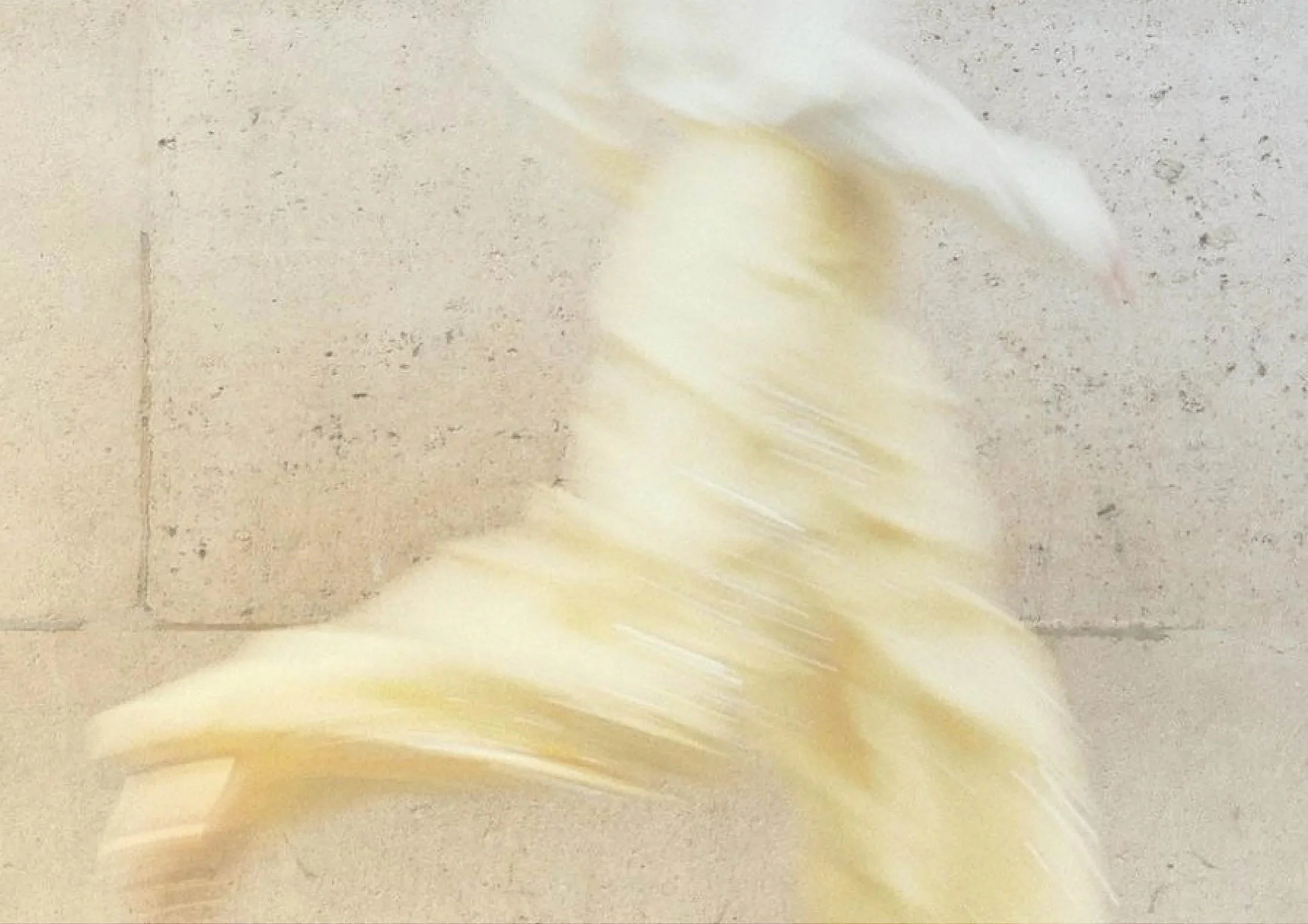 Blurred motion of a spinning yellow object against a beige textured wall.