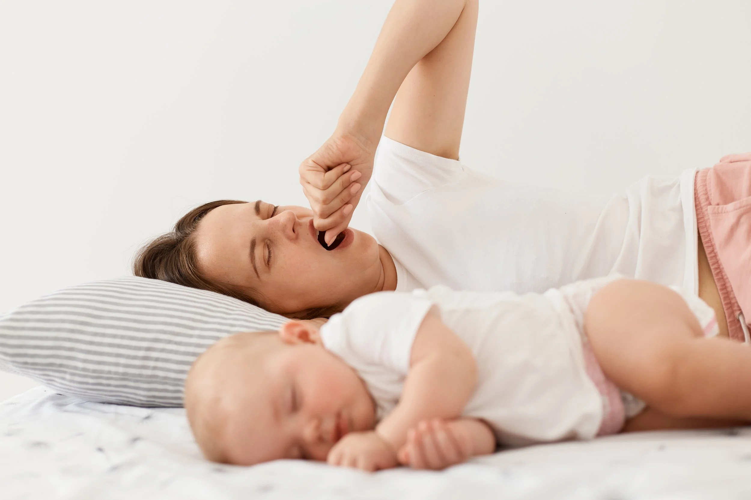 Mother and baby resting together in bed during a calm morning routine, representing gentle baby sleep support and helping babies sleep better through responsive, no cry-it-out methods.
