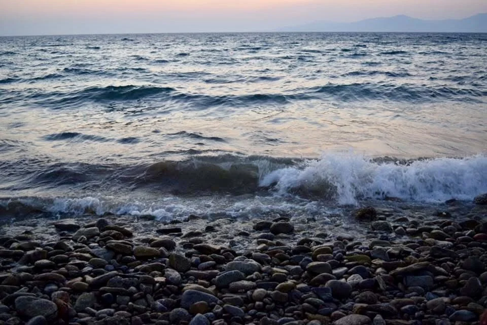 Ocean waves crashing onto a rocky beach during sunset