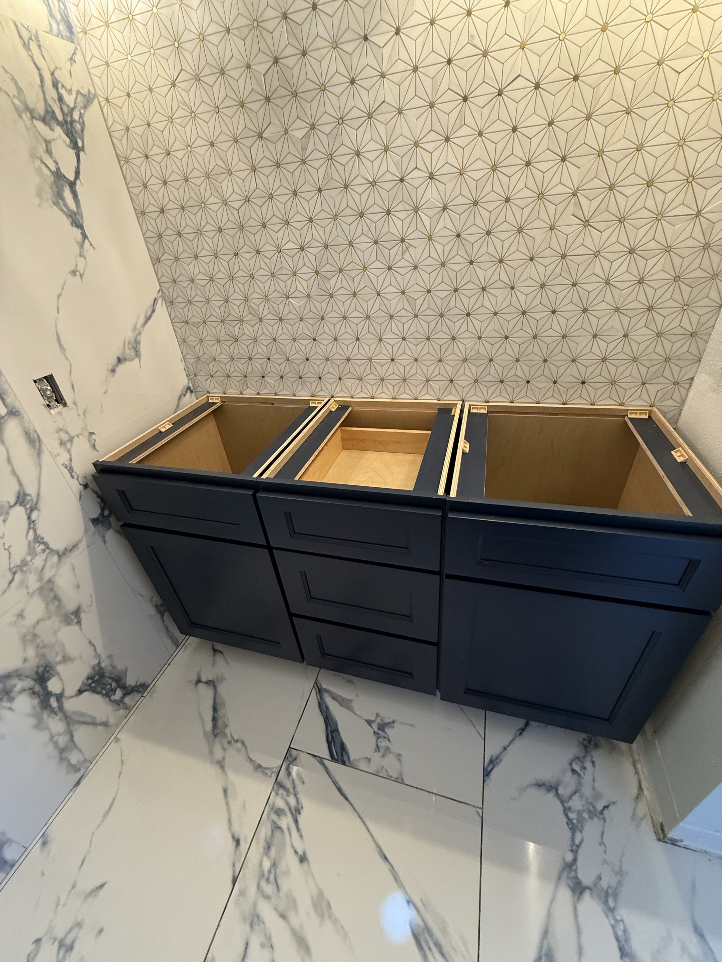 Open blue cabinet with drawers and marble floor and wall tiles in the background.