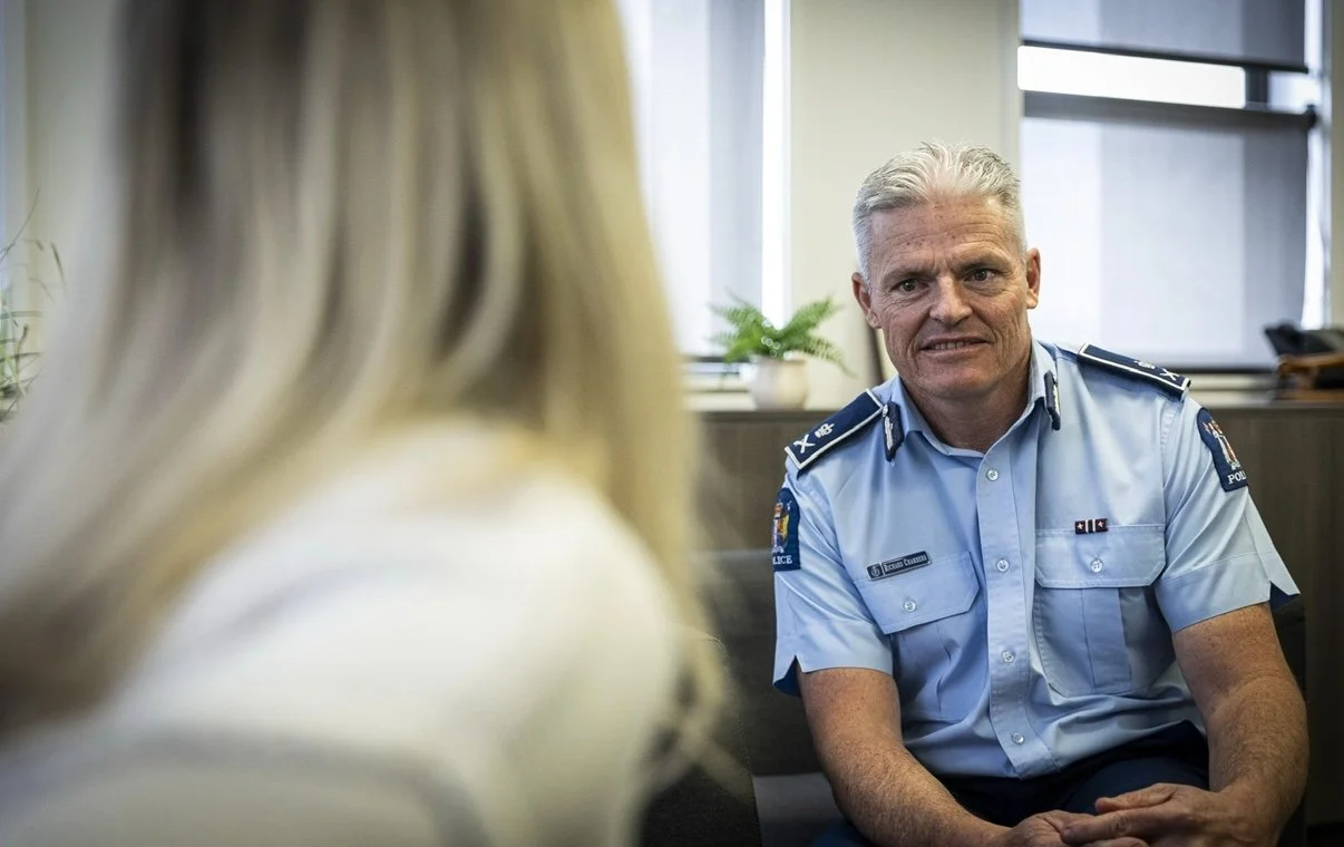 A police officer in uniform having a conversation with a woman in an office setting.
