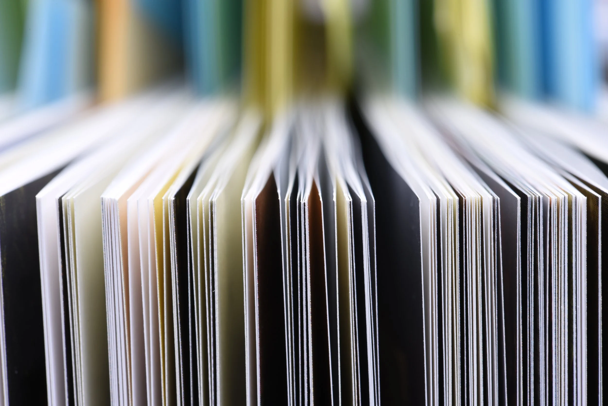 Close-up of a stack of opened colorful books with pages fanned out.