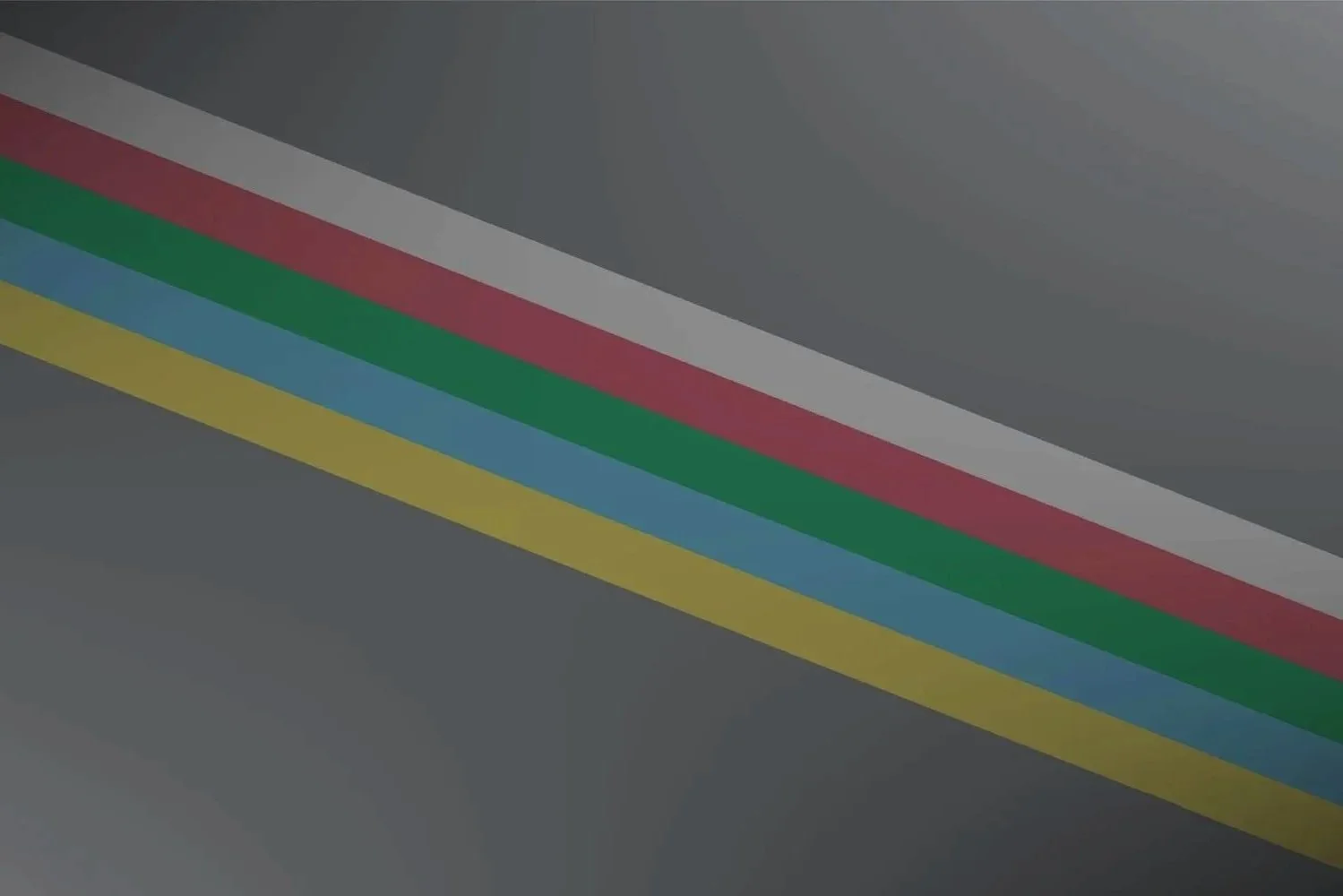 Close-up of a gray surface with five colored stripes in white, red, green, blue, and yellow running diagonally across it.