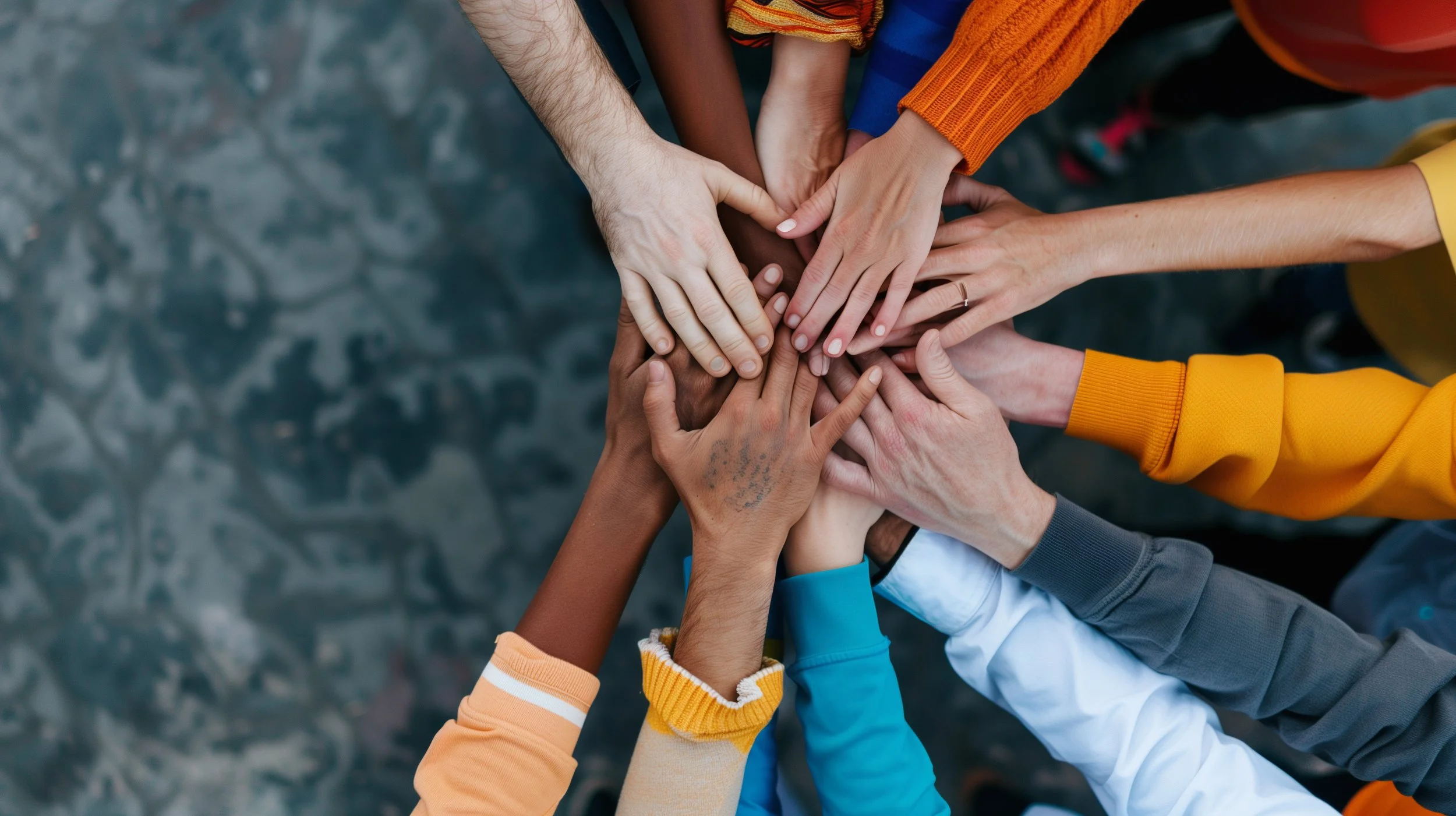 Multiple hands from diverse individuals stacked together in the center, symbolizing unity and teamwork.