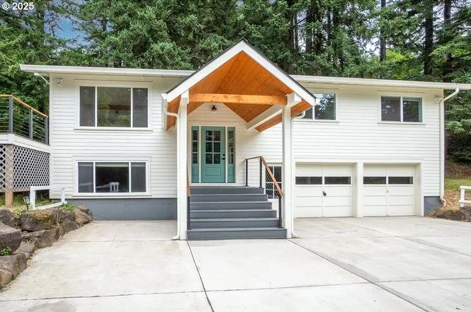 Two-story Beaverton home with freshly painted white exterior and custom light blue front door, residential exterior painting by Cascade Painting