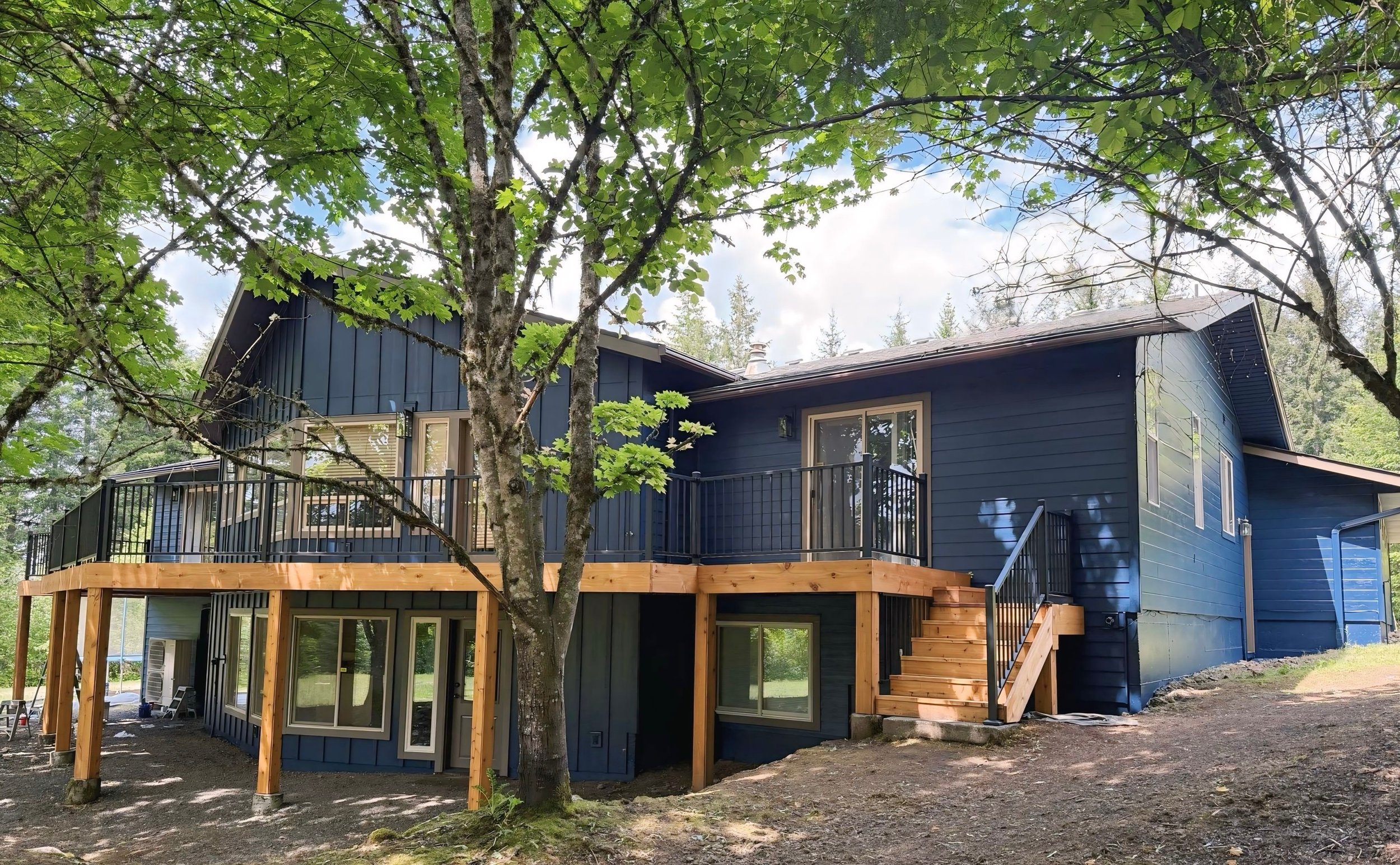 Two-story home freshly painted blue with stained wooden deck in Westside Portland, exterior work by Cascade Painting