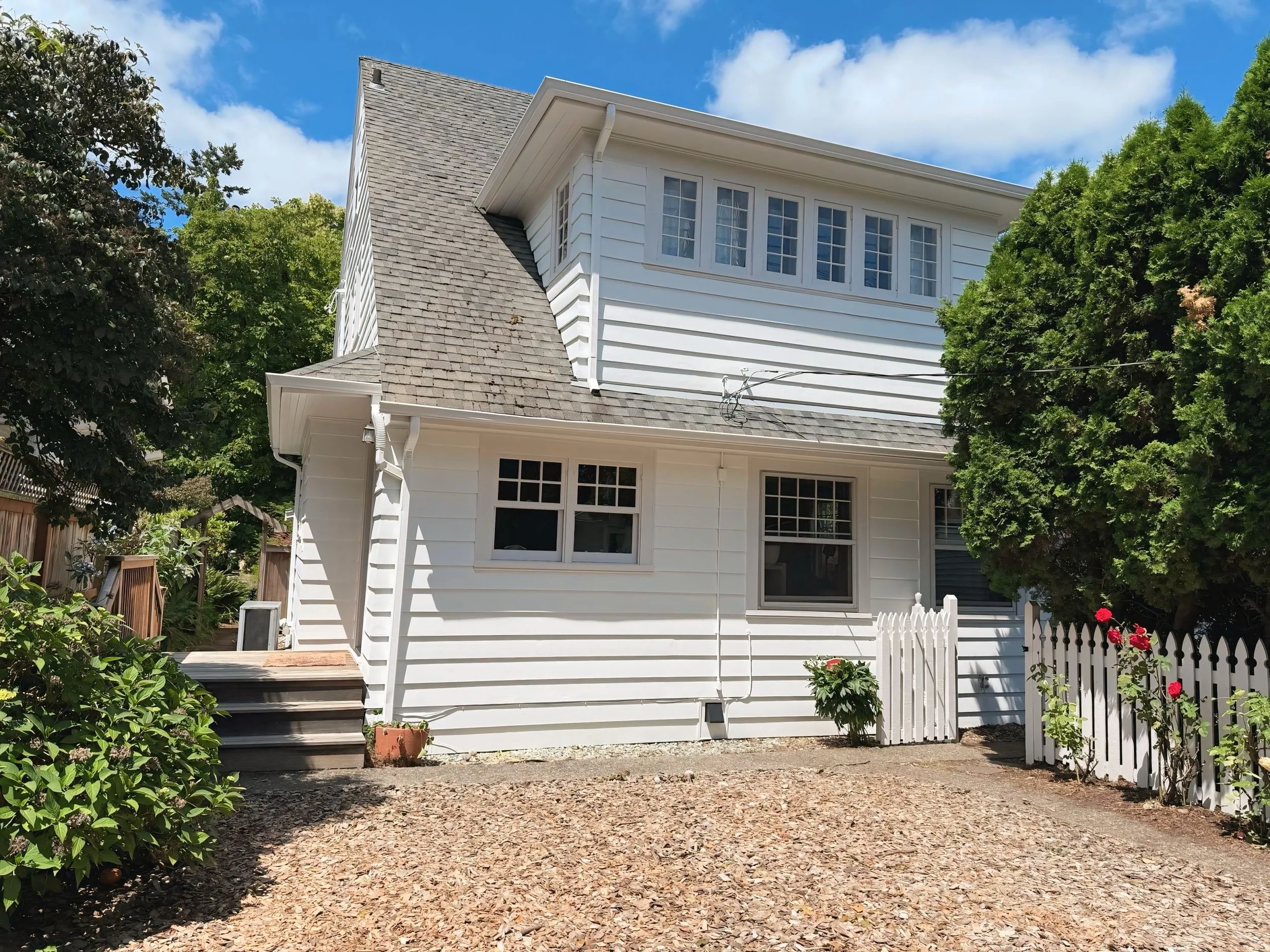 Two-story Beaverton home with freshly painted white exterior and gray shingle roof, exterior repaint by Cascade Painting