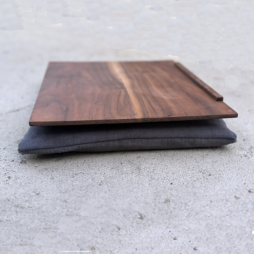 A wooden serving board placed on top of a dark grey cloth, both resting on a concrete surface.