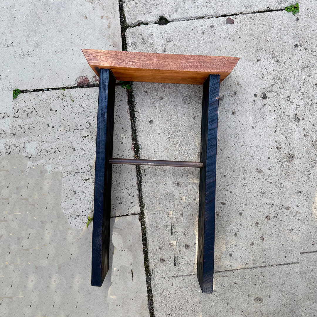 A small wooden side table with a rectangular top and dark legs, placed on a concrete sidewalk.