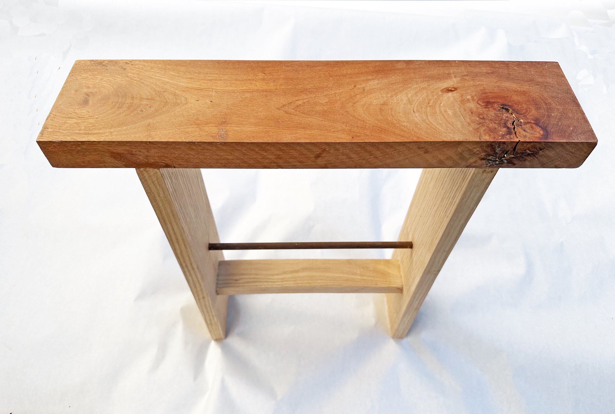 A wooden table with a rectangular top and four legs, placed on a white surface.