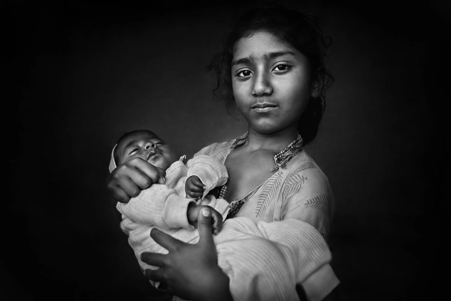 Standing portrait of Indian girl hugging a baby