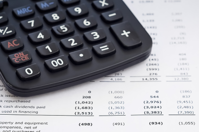 Close-up of a black calculator with gray and red buttons on a financial report or spreadsheet.