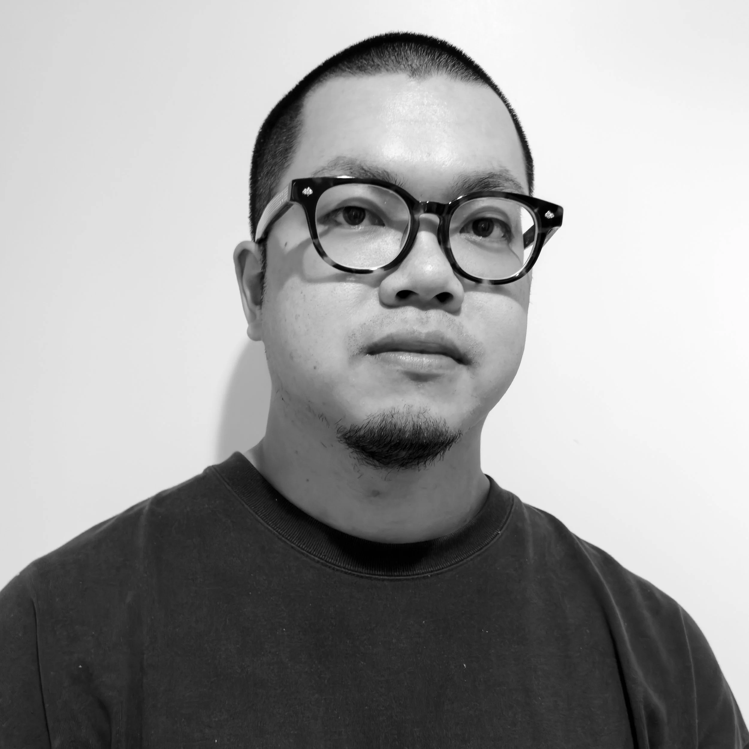黒縁メガネをかけた男性のポートレート写真。白い背景。