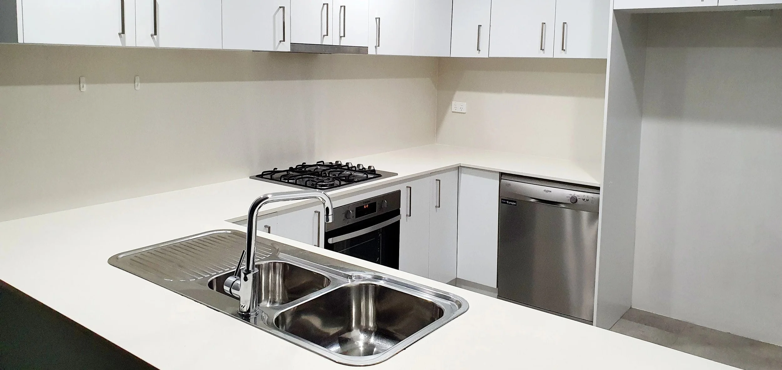 Modern kitchen with white cabinets, a stainless steel sink, a gas stove, an oven, and a dishwasher.