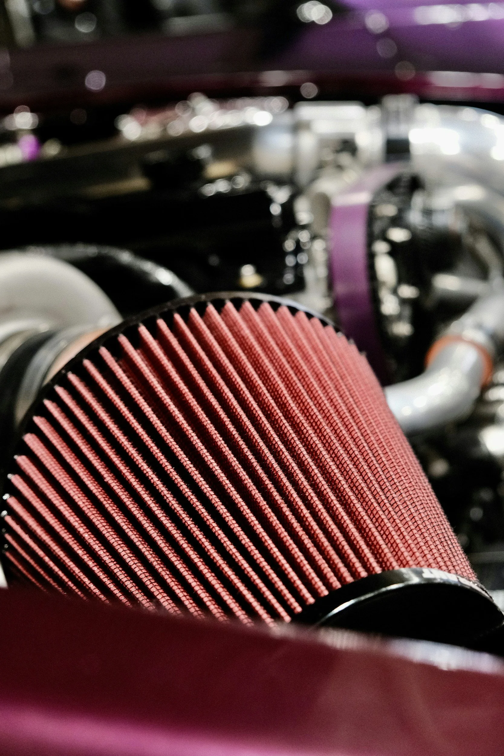 Close-up of a red high-performance air filter in an engine compartment.