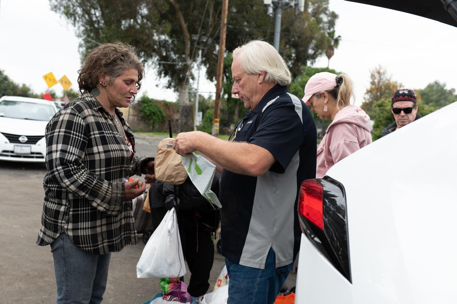 People in a parking lot exchanging items or supplies
