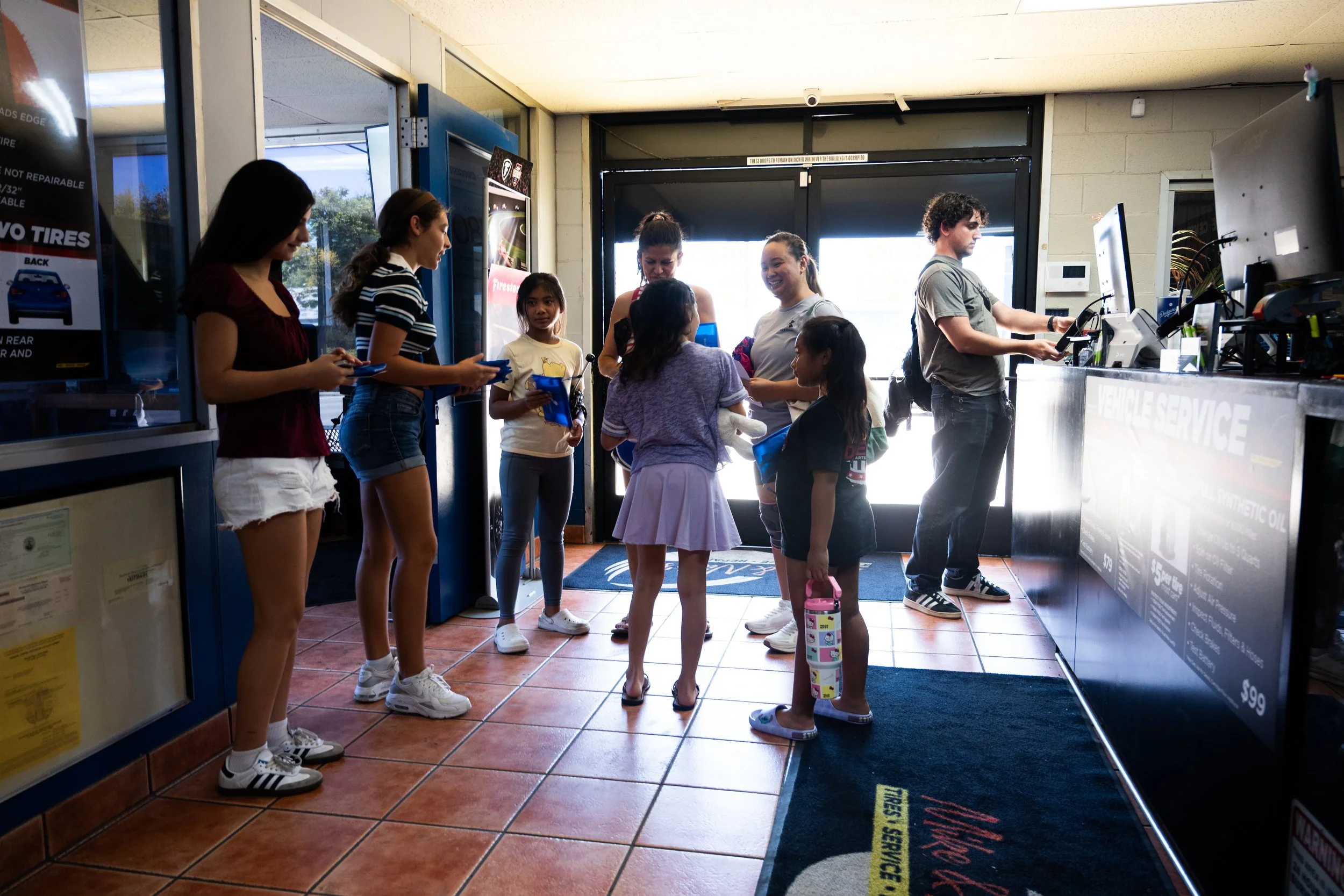 People standing in line at the counter inside a car service center.