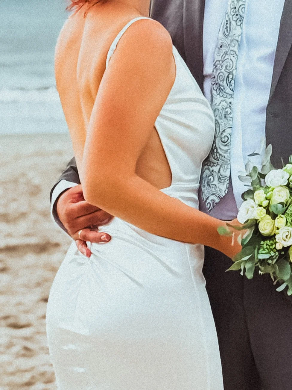 Brautpaar bei einer Strandhochzeit, Braut mit Blumenstrauß, Bräutigam im Anzug