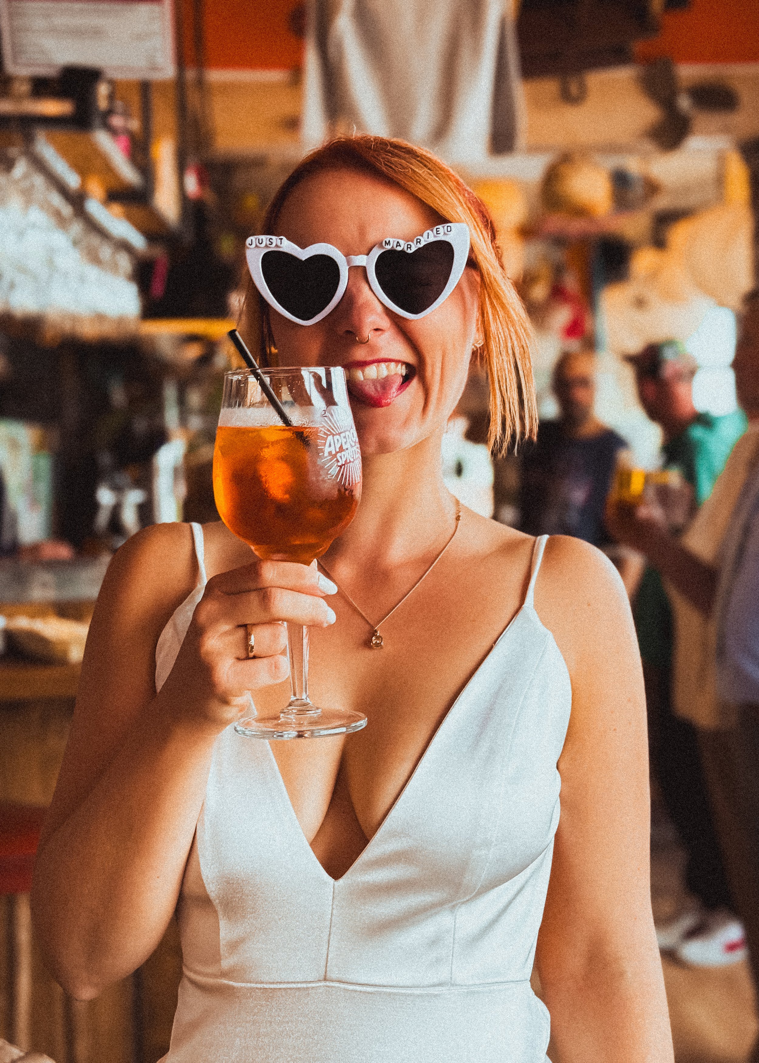 Braut trinkt einen Aperol und lacht auf ihrer Hochzeit.