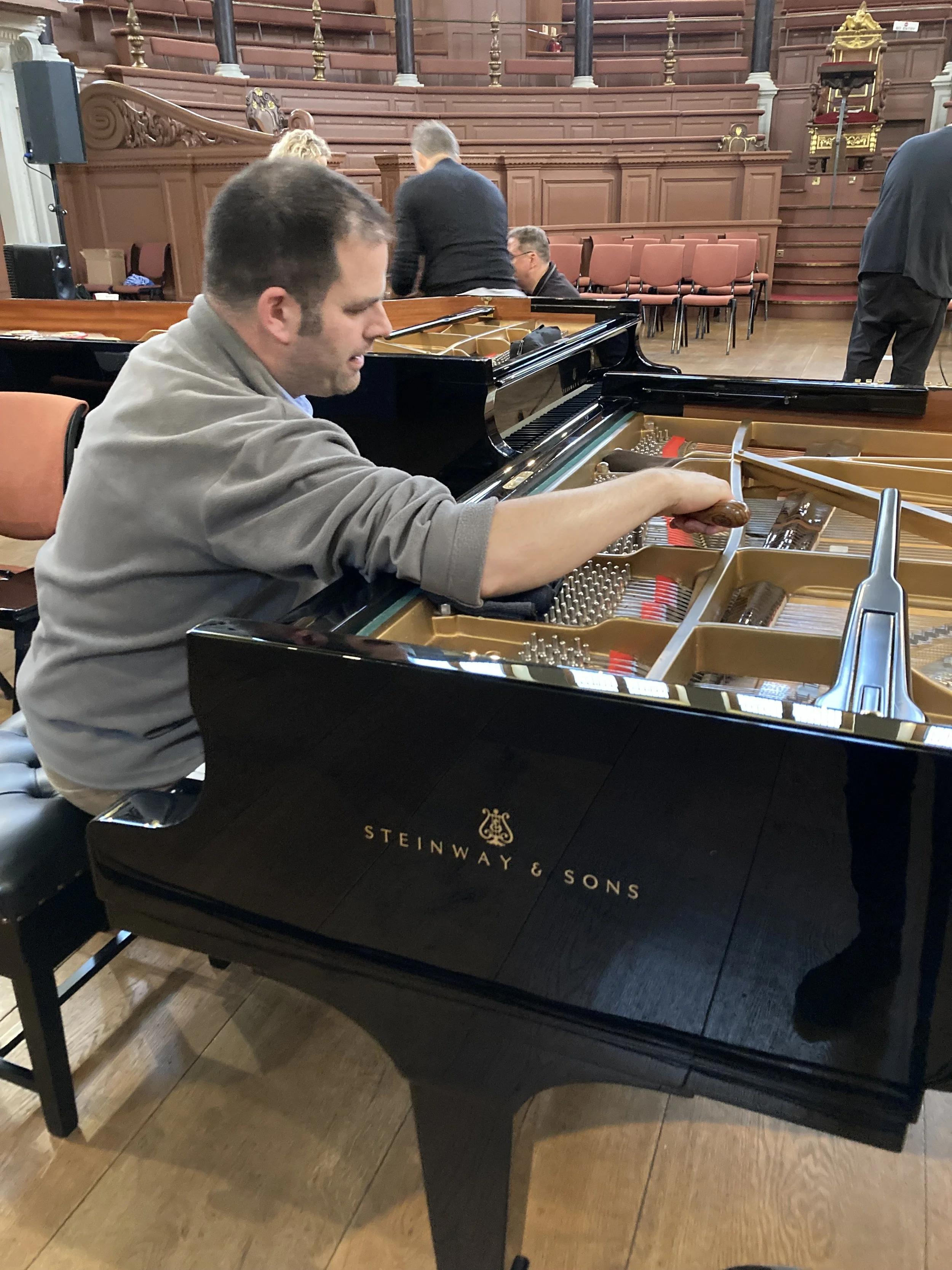 Joe sat tuning a Steinway piano.