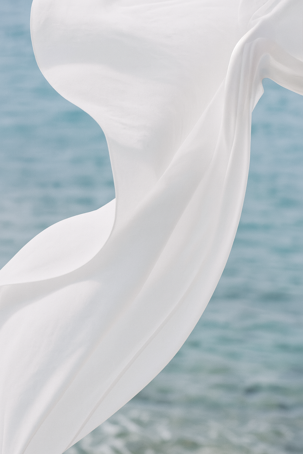 Close-up of white fabric or sculpture against a blurred blue water background.