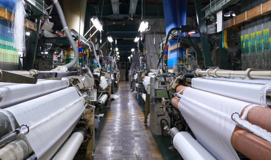 Industrial textile manufacturing with large machinery and fabric rollers in a factory
