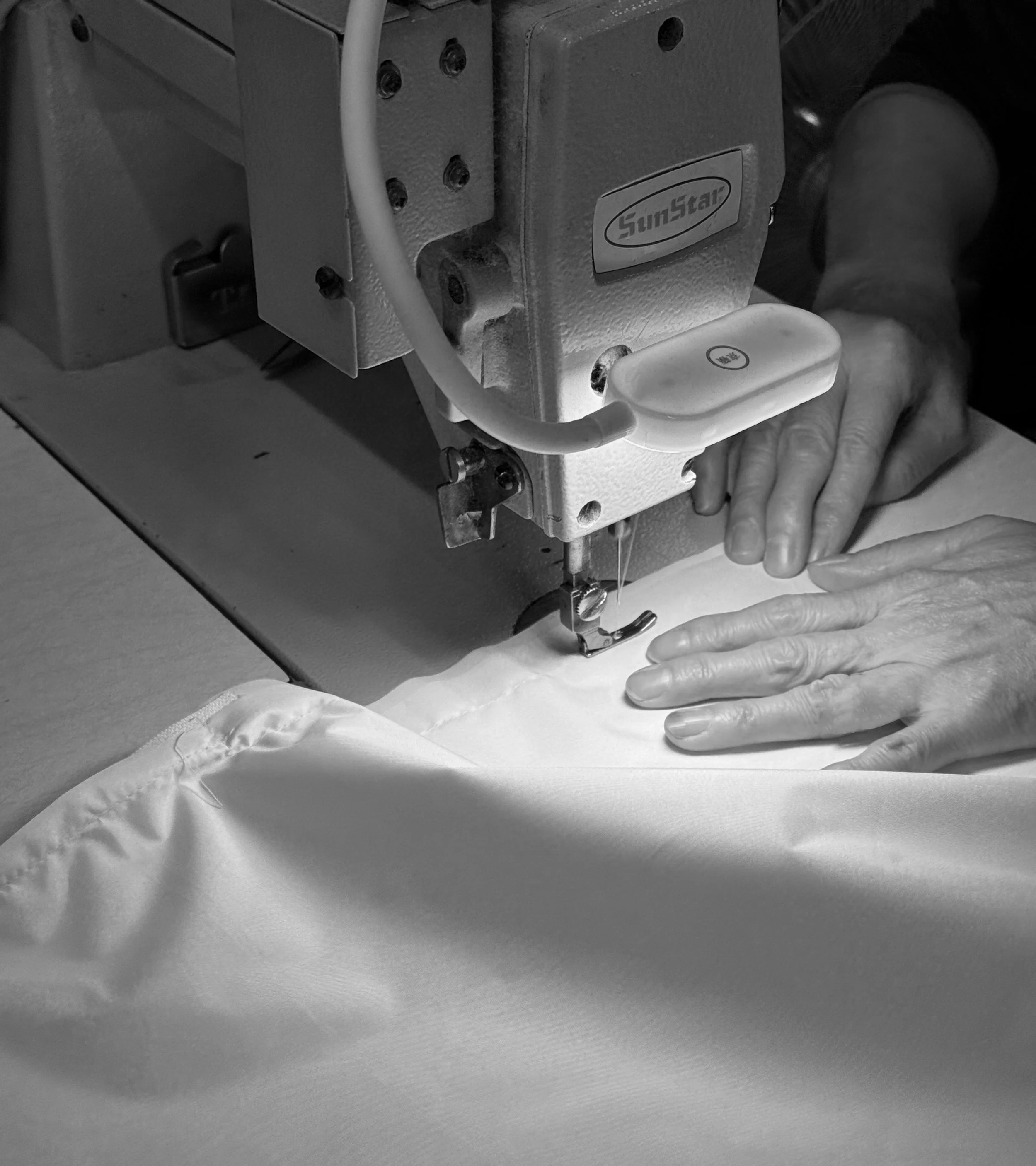 A person sewing fabric using industrial sewing machine.