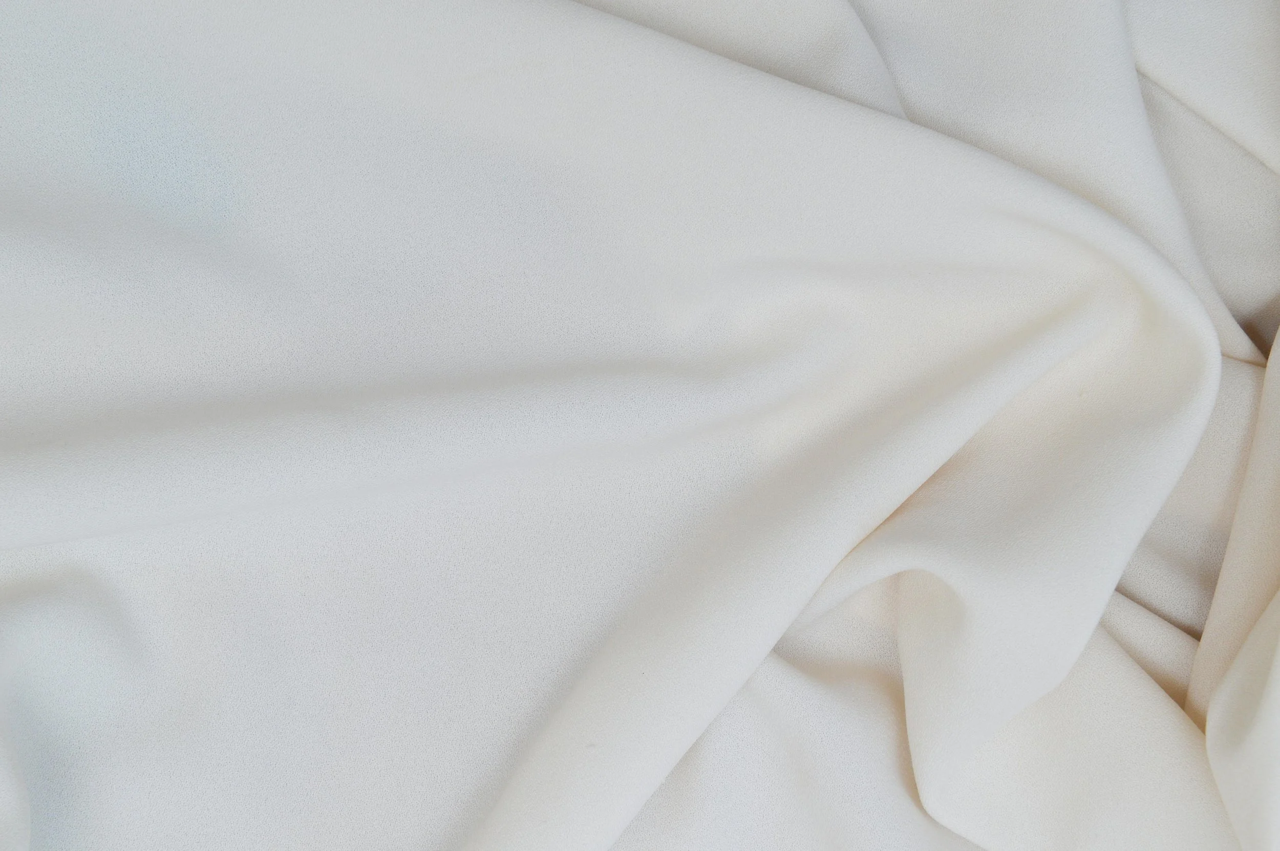 Close-up of soft, white fabric with gentle folds and creases.