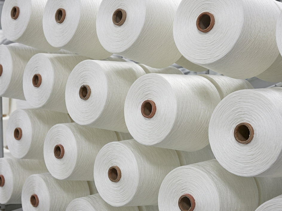 Multiple large spools of white thread stacked on a shelf.