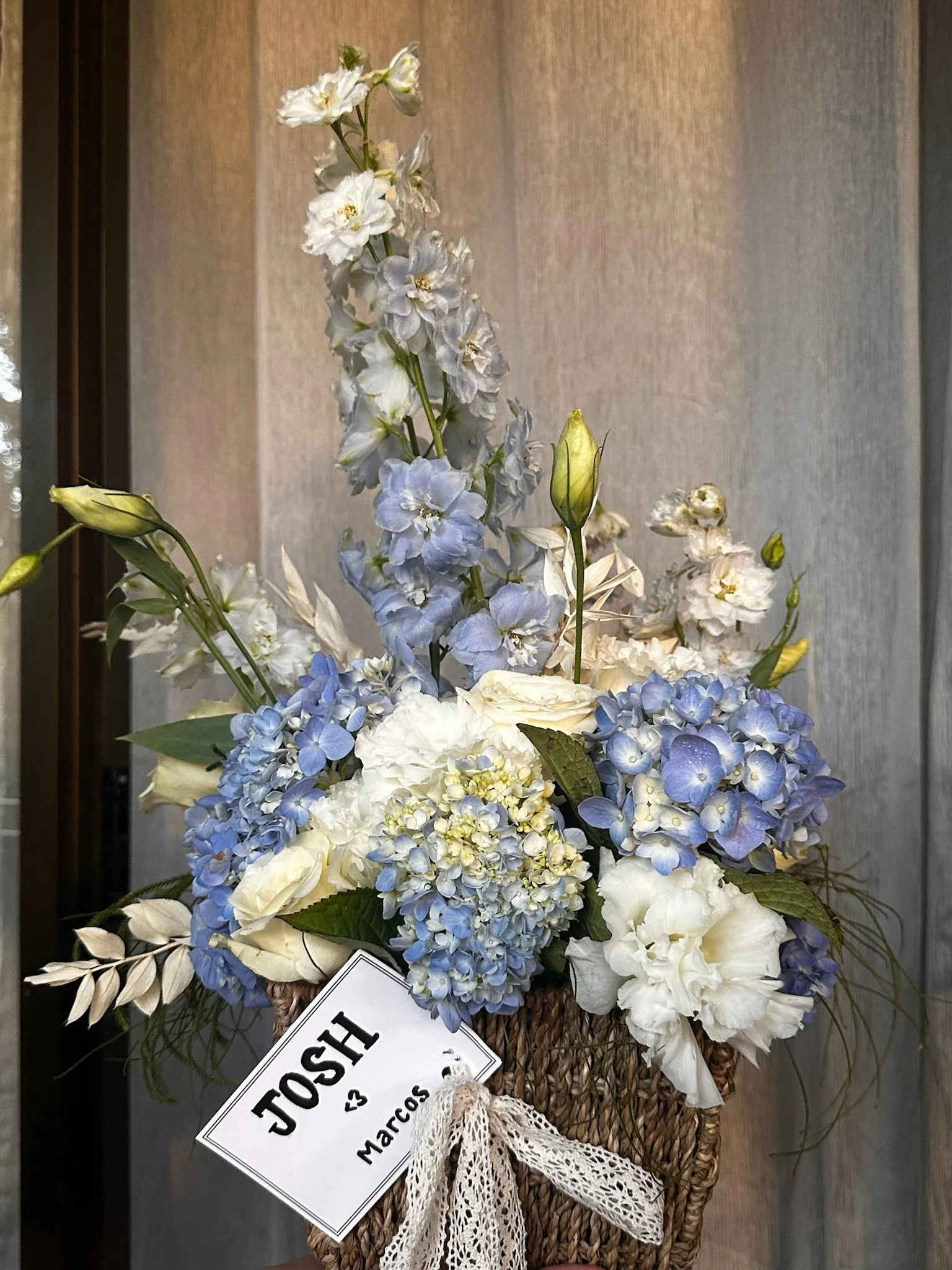 A bouquet of white and light blue flowers with a lace ribbon, with personalised tag