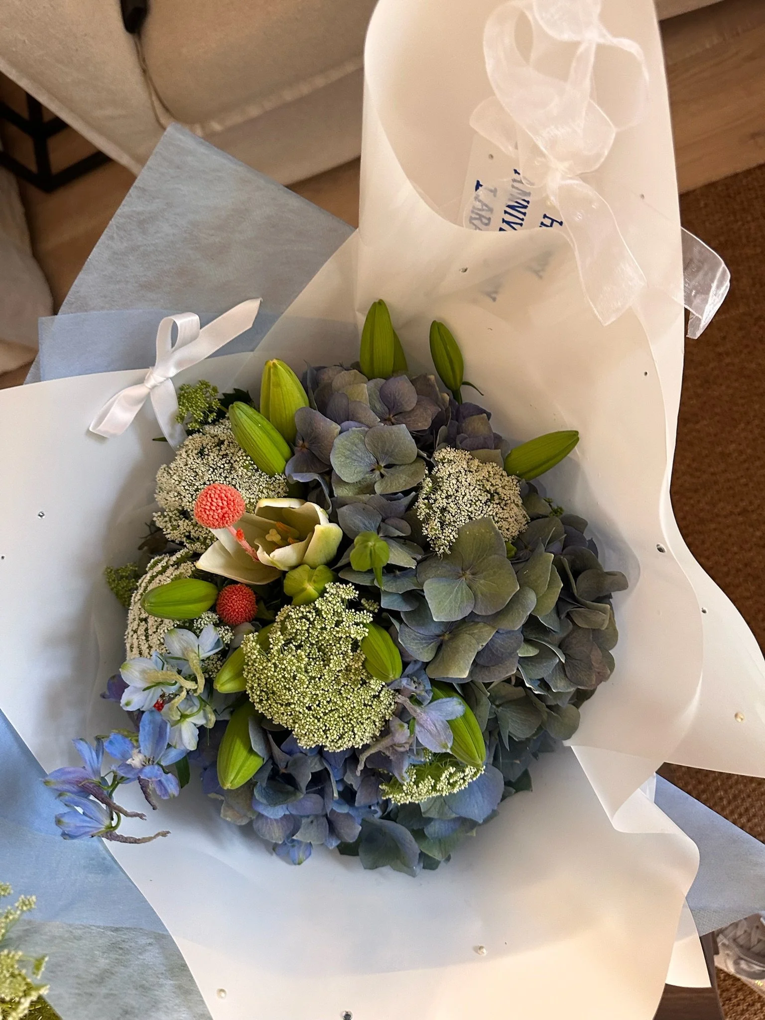 Close-up of a bouquet of mixed flowers wrapped in white and blue paper.