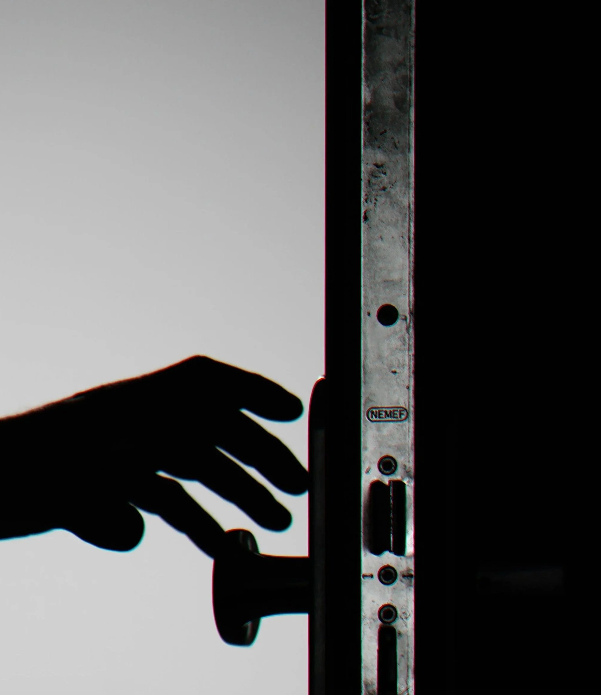 Close-up of a metallic measuring tool, marked with the brand name 'NEMEF', held by a hand, with a background divided into dark and light sections.