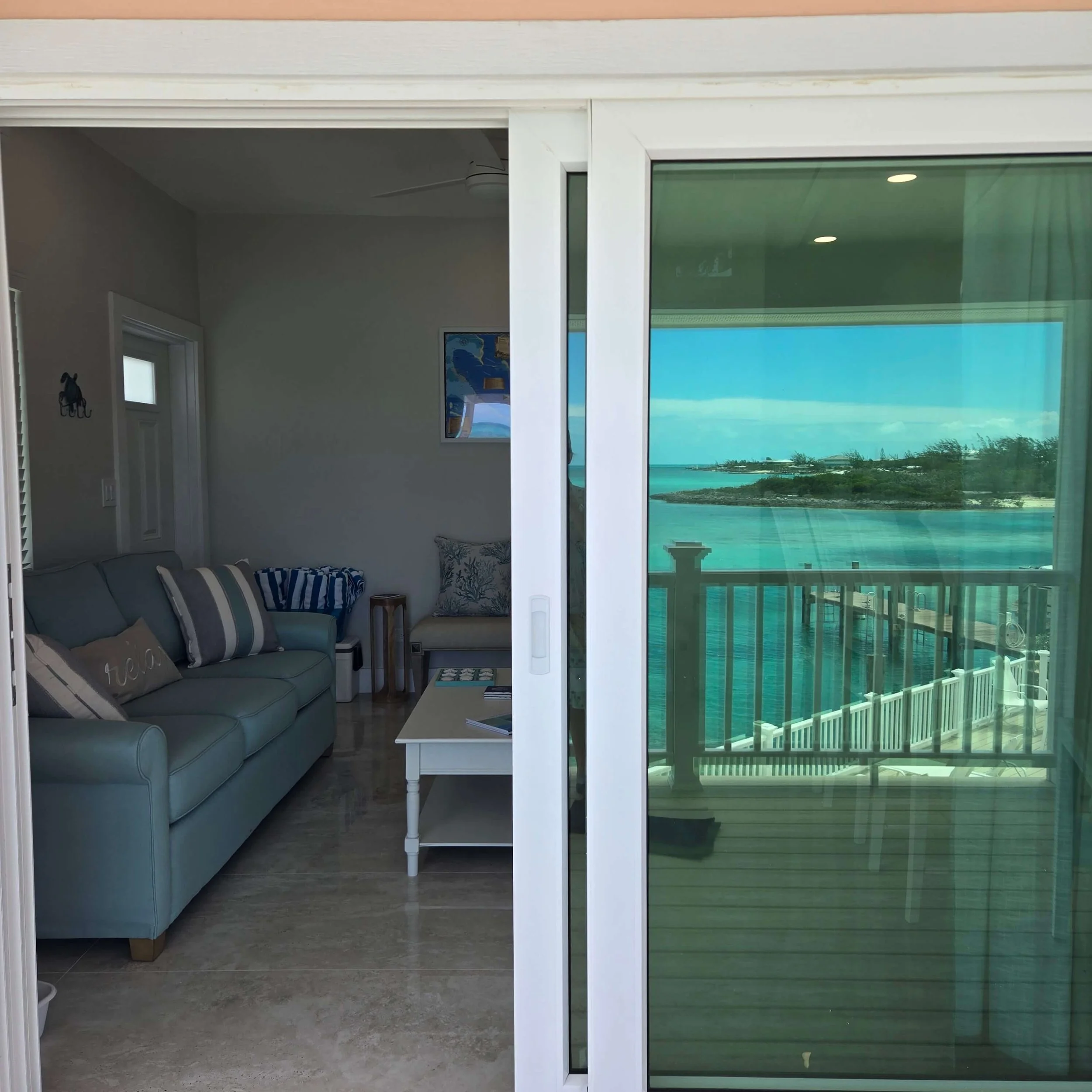 View of a balcony and ocean through sliding glass door in a coastal home.